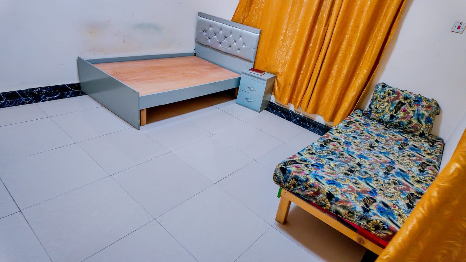 Bedroom with a double bed frame, bedside cabinet and a day bed beside the window