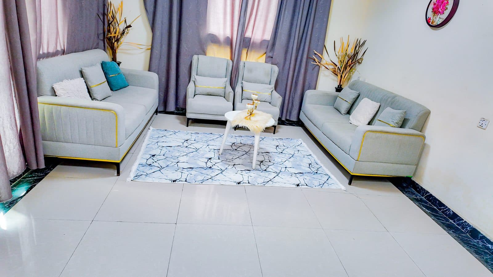 Living room with two grey sofas and matching armchairs arranged around a patterned rug